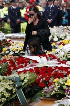Relatives of victims cry over coffins as they attend a state ...