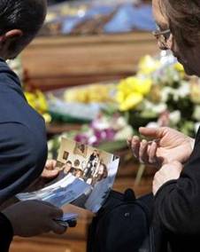 Mourners look at pictures of their relatives after a state funeral ...