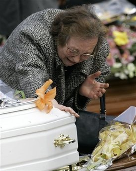 A woman reacts as she touches the white coffin of a child, during ...
