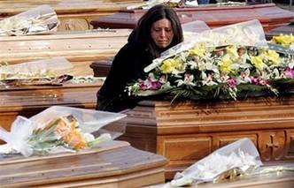A woman kneels between coffins prior to the funerals for quake ...