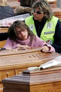 A women reacts over a coffin as a field psychologist, at right ...