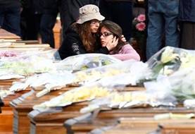 Two women react, between coffins prior to the funerals for quake ...