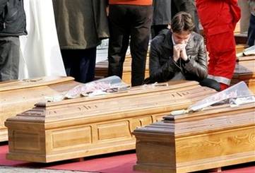 A man seenbetween coffins at the funerals for quake victims ...