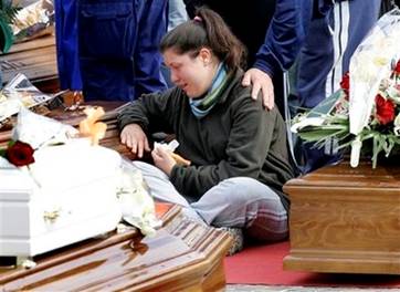 A young woman reacts between coffins at the funerals for quake ...